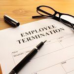 Close-up of an employee termination document with a pen and glasses on a desk.